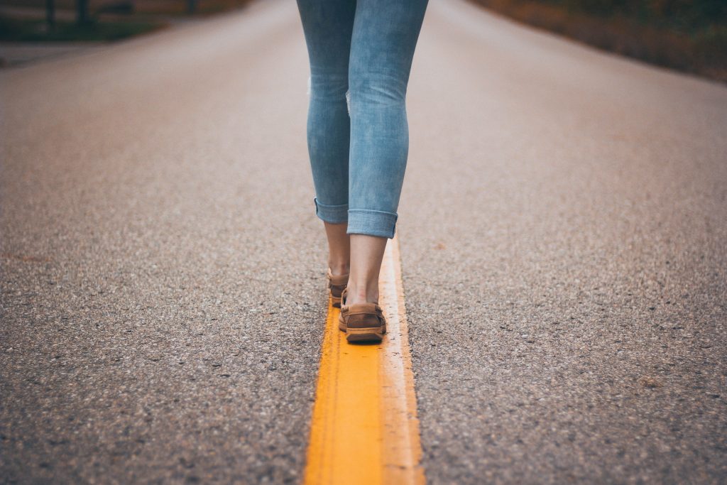 Woman's feet walking down the middle of the road